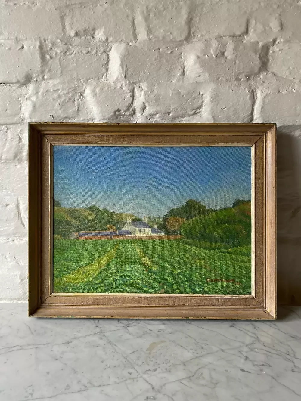 Framed painting of a landscape with a house and fields on a stone wall ,available to buy from the-salon.com. SALON curates the finest unique handmade pieces from the interior industry's best makers and brands. Shop luxury furniture, lighting, rugs, art, antiques and vintage pieces and accessories from SALON interior designed rooms.