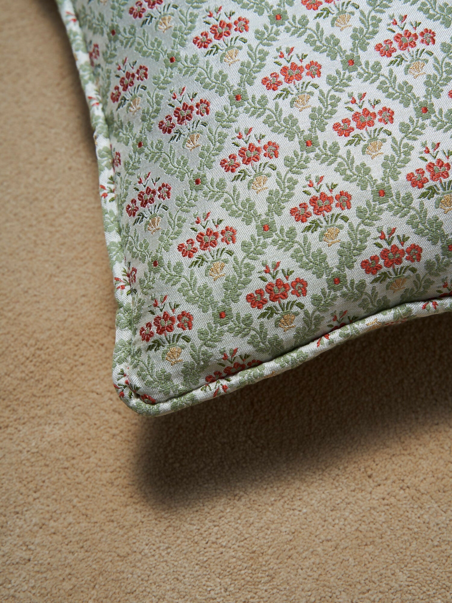 A close up of the green floral patterned pillow on a brown background,  available  to buy on the-salon.com. SALON curates the finest , unique, handmade pieces from the interior industry's best makers and brands. Shop luxury furniture, lighting, rugs, art, antiques and vintage pieces and accessories from SALON interior designed rooms.