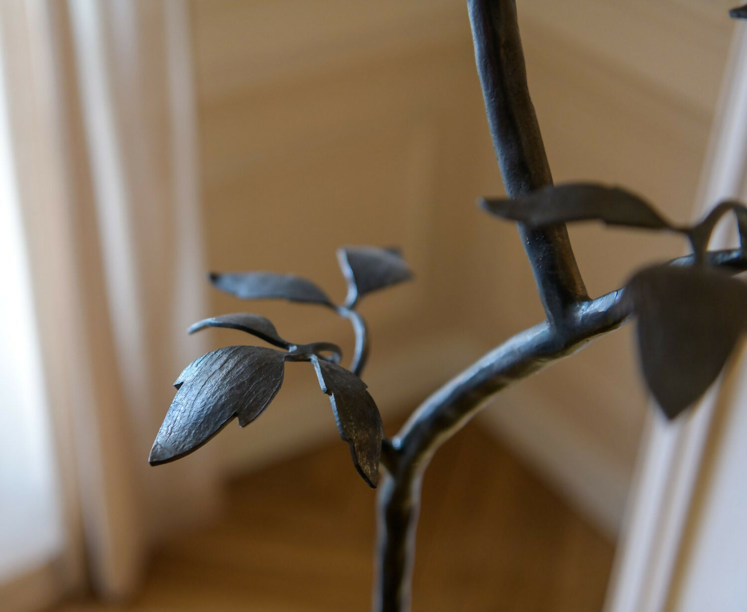 Decorative metal plant with leaves against a blurred indoor background, available  to buy on the-salon.com. SALON curates the finest , unique, handmade pieces from the interior industry's best makers and brands. Shop luxury furniture, lighting, rugs, art, antiques and vintage pieces and accessories from SALON interior designed rooms.