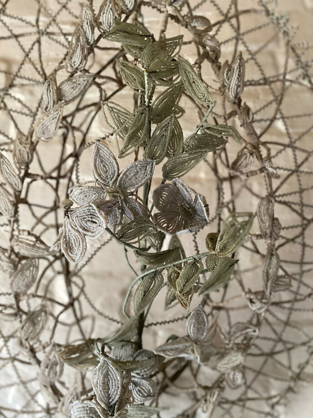 Decorative metallic leaf branch against a textured beige background,  available  to buy on the-salon.com. SALON curates the finest , unique, handmade pieces from the interior industry's best makers and brands. Shop luxury furniture, lighting, rugs, art, antiques and vintage pieces and accessories from SALON interior designed rooms.