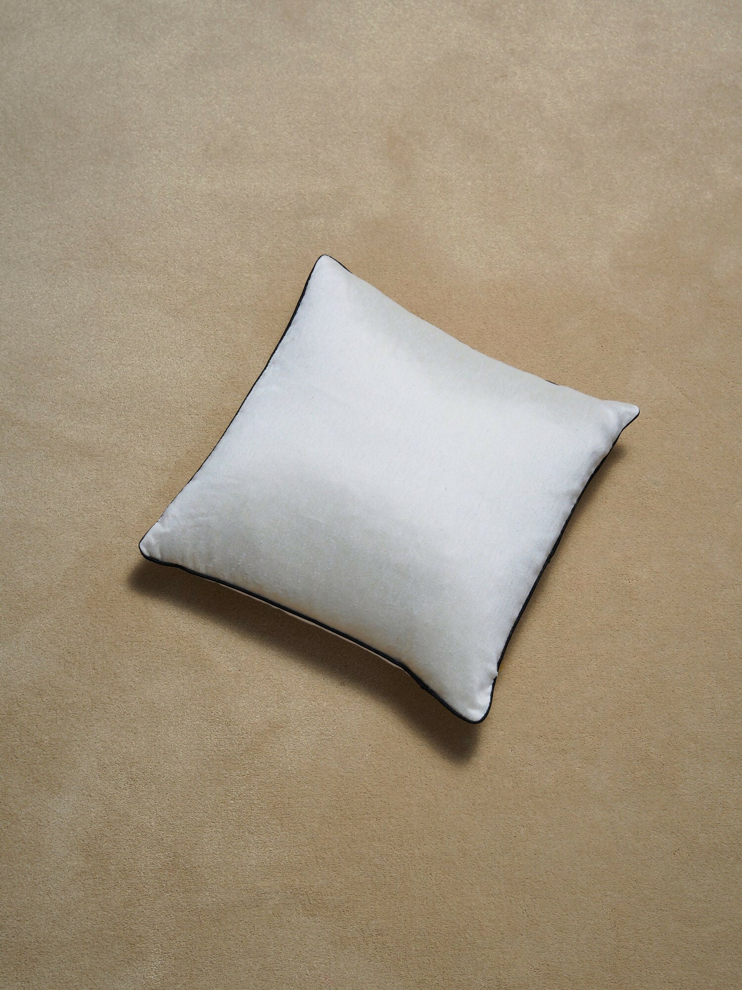 White pillow on a beige background,  available  to buy on the-salon.com. SALON curates the finest , unique, handmade pieces from the interior industry's best makers and brands. Shop luxury furniture, lighting, rugs, art, antiques and vintage pieces and accessories from SALON interior designed rooms.