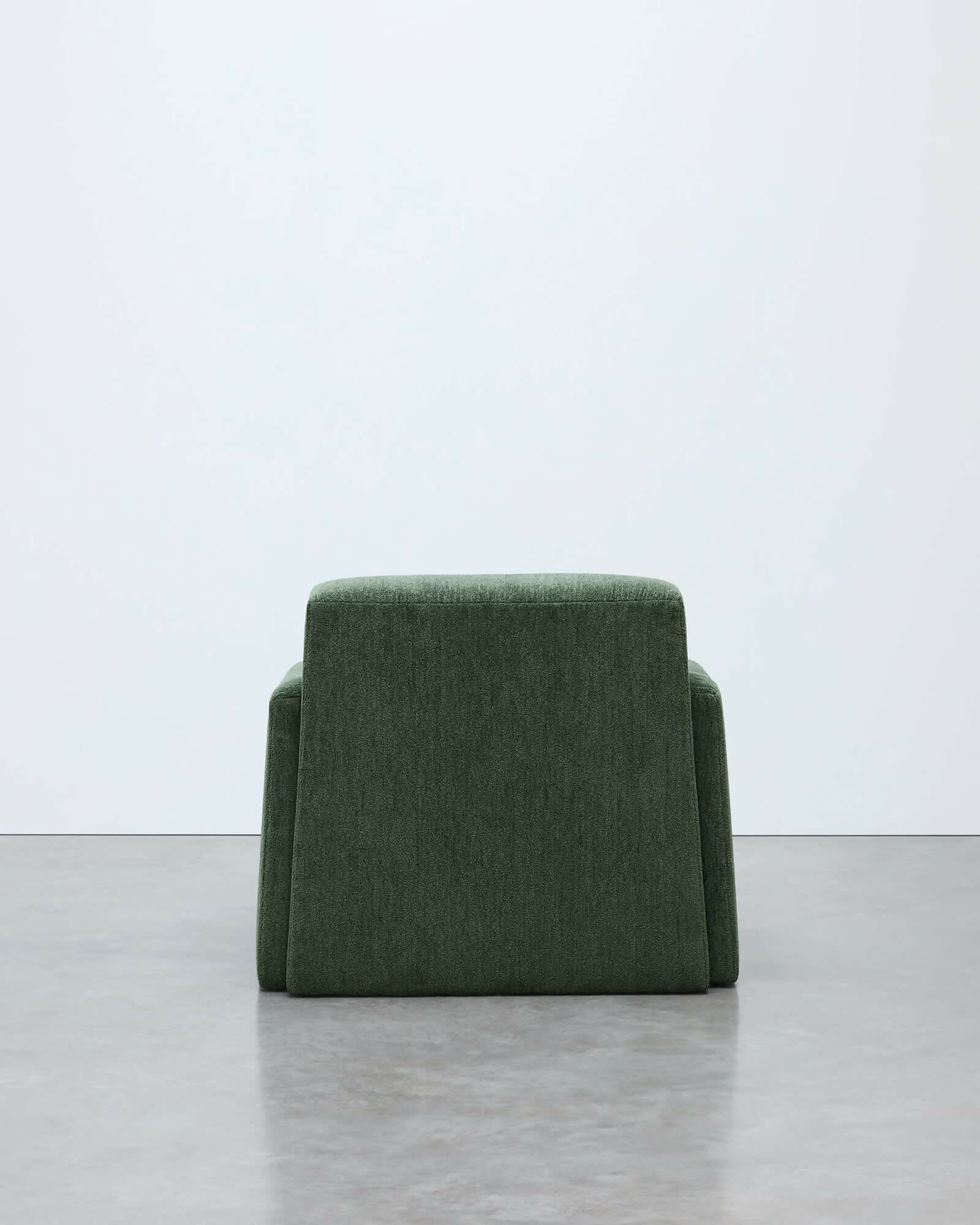 Green arm chair on a light gray surface with a white background, available  to buy on the-salon.com. SALON curates the finest , unique, handmade pieces from the interior industry's best makers and brands. Shop luxury furniture, lighting, rugs, art, antiques and vintage pieces and accessories from SALON interior designed rooms.