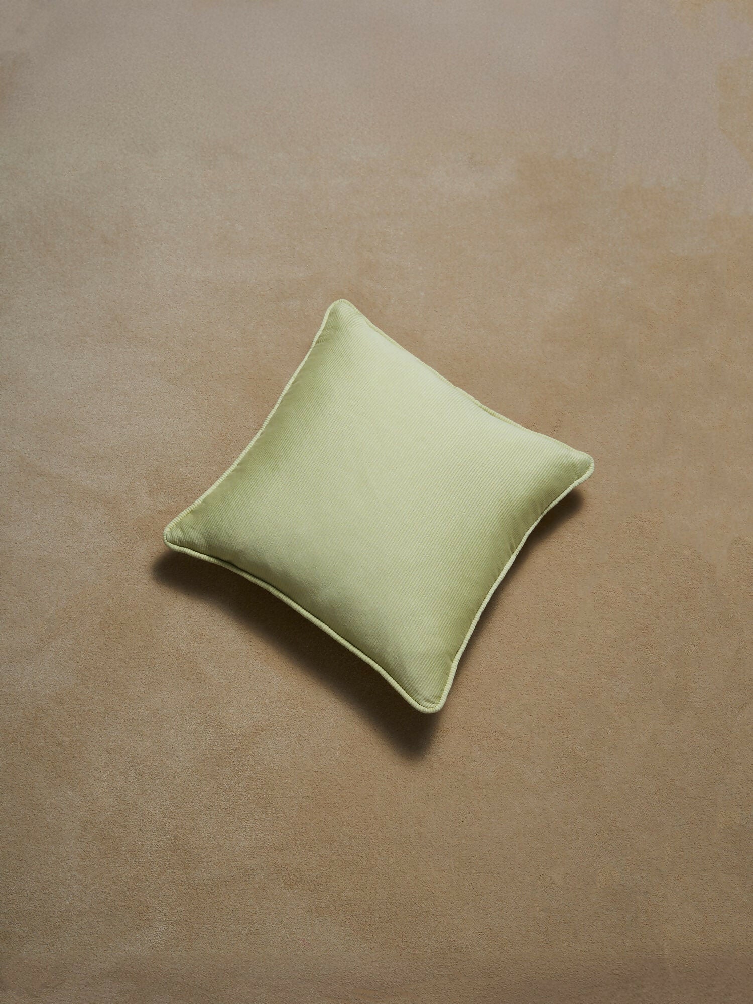 Green pillow on a brown textured surface,  available  to buy on the-salon.com. SALON curates the finest , unique, handmade pieces from the interior industry's best makers and brands. Shop luxury furniture, lighting, rugs, art, antiques and vintage pieces and accessories from SALON interior designed rooms.