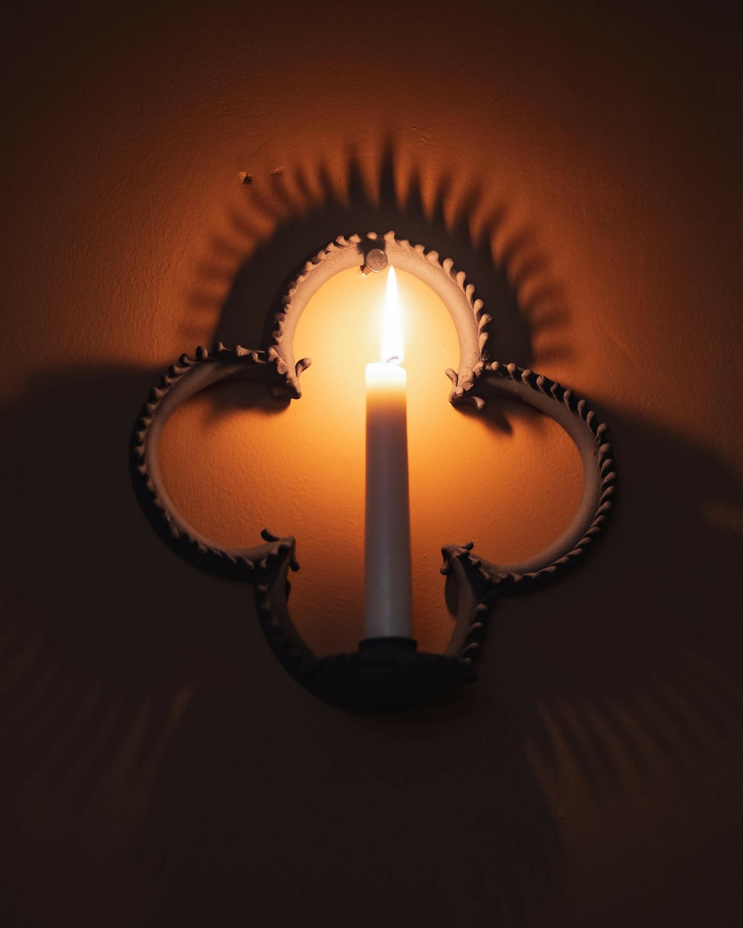 Decorative wall sconce with a candle casting shadows on a wall,  available  to buy on the-salon.com. SALON curates the finest , unique, handmade pieces from the interior industry's best makers and brands. Shop luxury furniture, lighting, rugs, art, antiques and vintage pieces and accessories from SALON interior designed rooms.