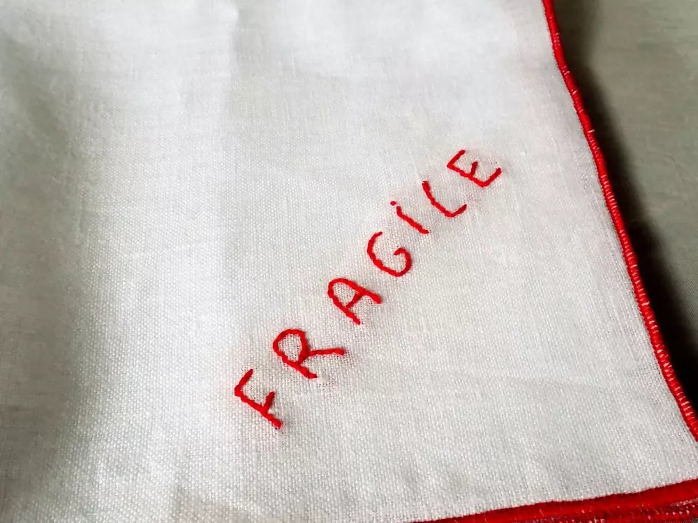 White fabric with red 'FRAGILE' text on a plain background,  available  to buy on the-salon.com. SALON curates the finest , unique, handmade pieces from the interior industry's best makers and brands. Shop luxury furniture, lighting, rugs, art, antiques and vintage pieces and accessories from SALON interior designed rooms.