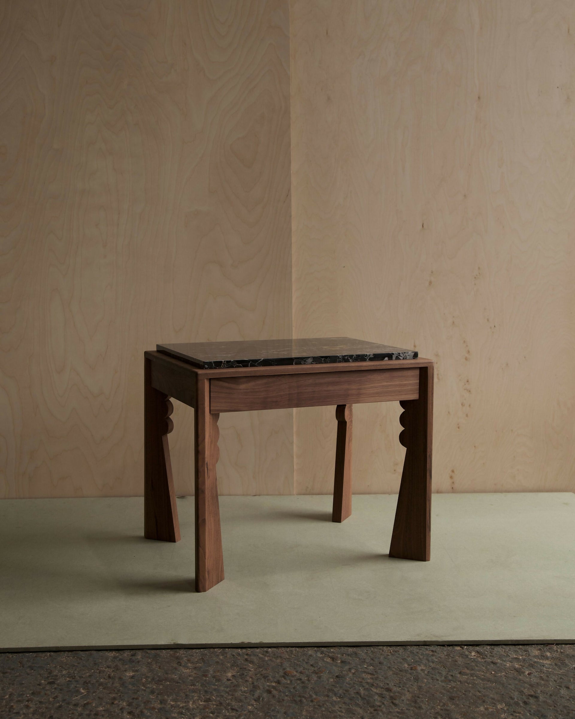 Wooden nightstand with a black marble top against a plain wall-available  to buy on the-salon.com. SALON curates the finest , unique, handmade pieces from the interior industry's best makers and brands. Shop luxury furniture, lighting, rugs, art, antiques and vintage pieces and accessories from SALON interior designed rooms.