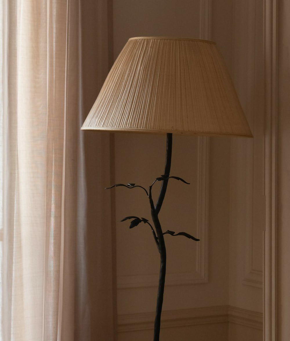 Floor lamp with a pleated beige shade against a neutral wall, available  to buy on the-salon.com. SALON curates the finest , unique, handmade pieces from the interior industry's best makers and brands. Shop luxury furniture, lighting, rugs, art, antiques and vintage pieces and accessories from SALON interior designed rooms.