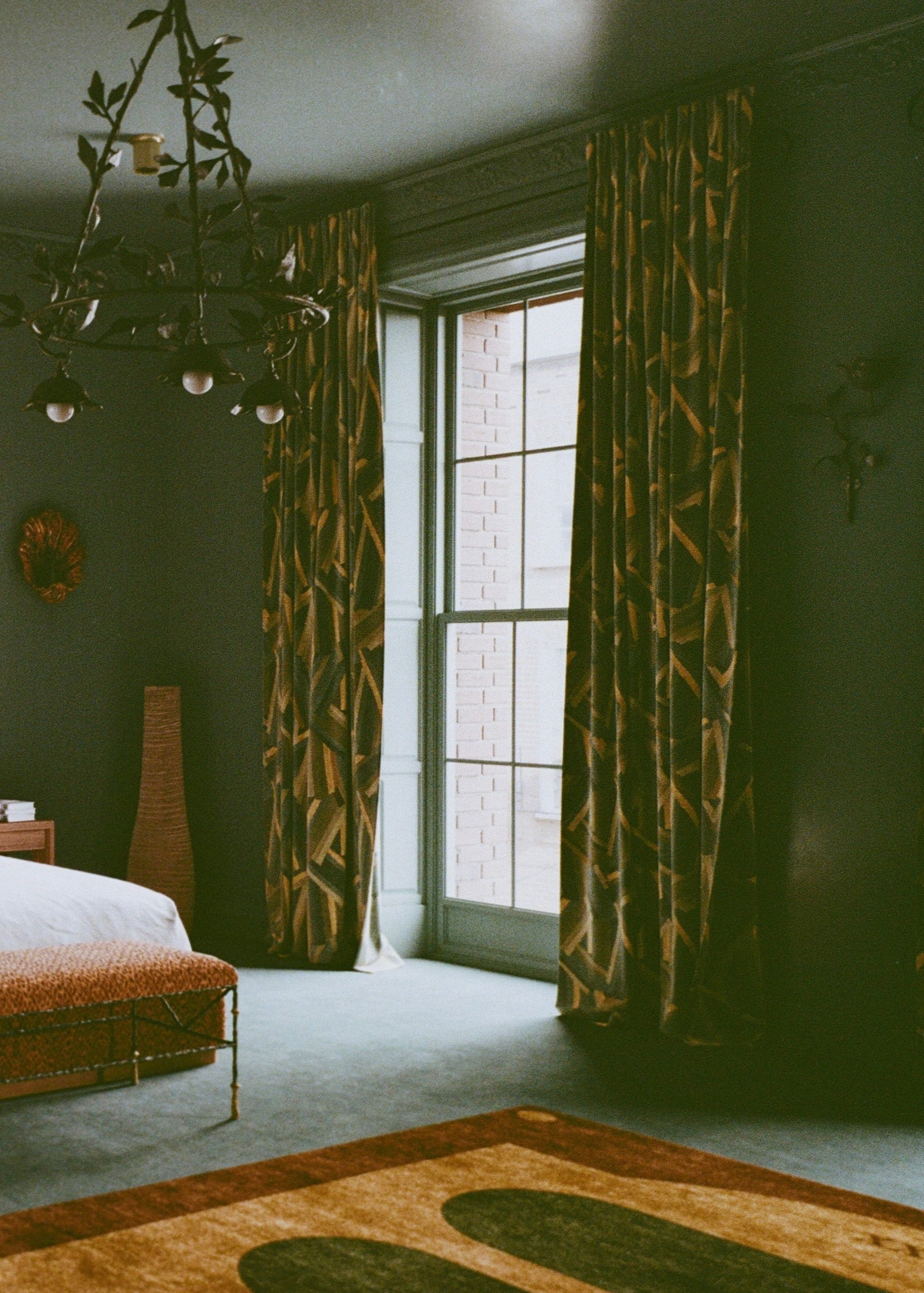 Room with patterned curtains, a rug, and a chandelier.
