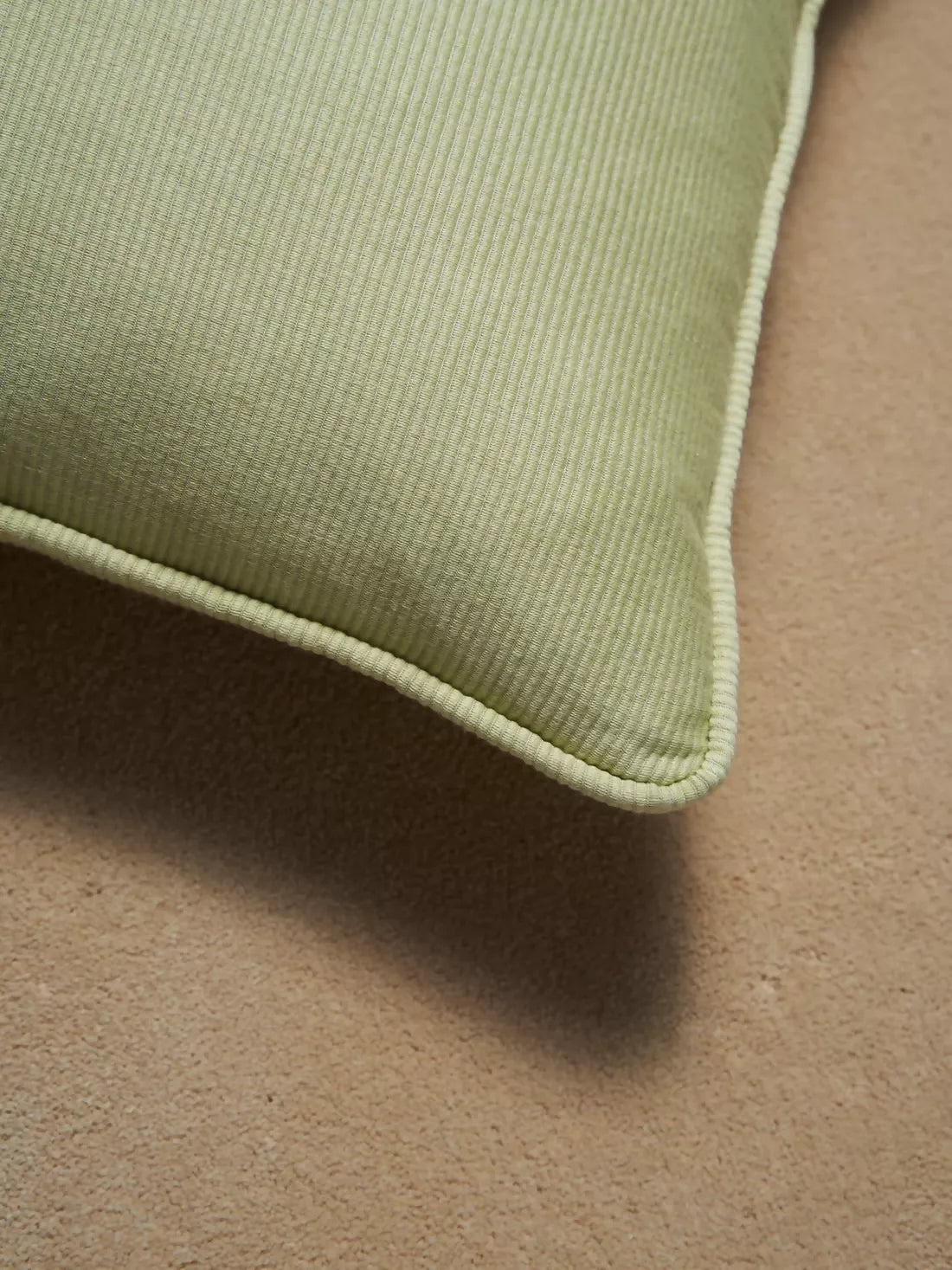 Close-up of a green cushion on a brown surface,  available  to buy on the-salon.com. SALON curates the finest , unique, handmade pieces from the interior industry's best makers and brands. Shop luxury furniture, lighting, rugs, art, antiques and vintage pieces and accessories from SALON interior designed rooms.