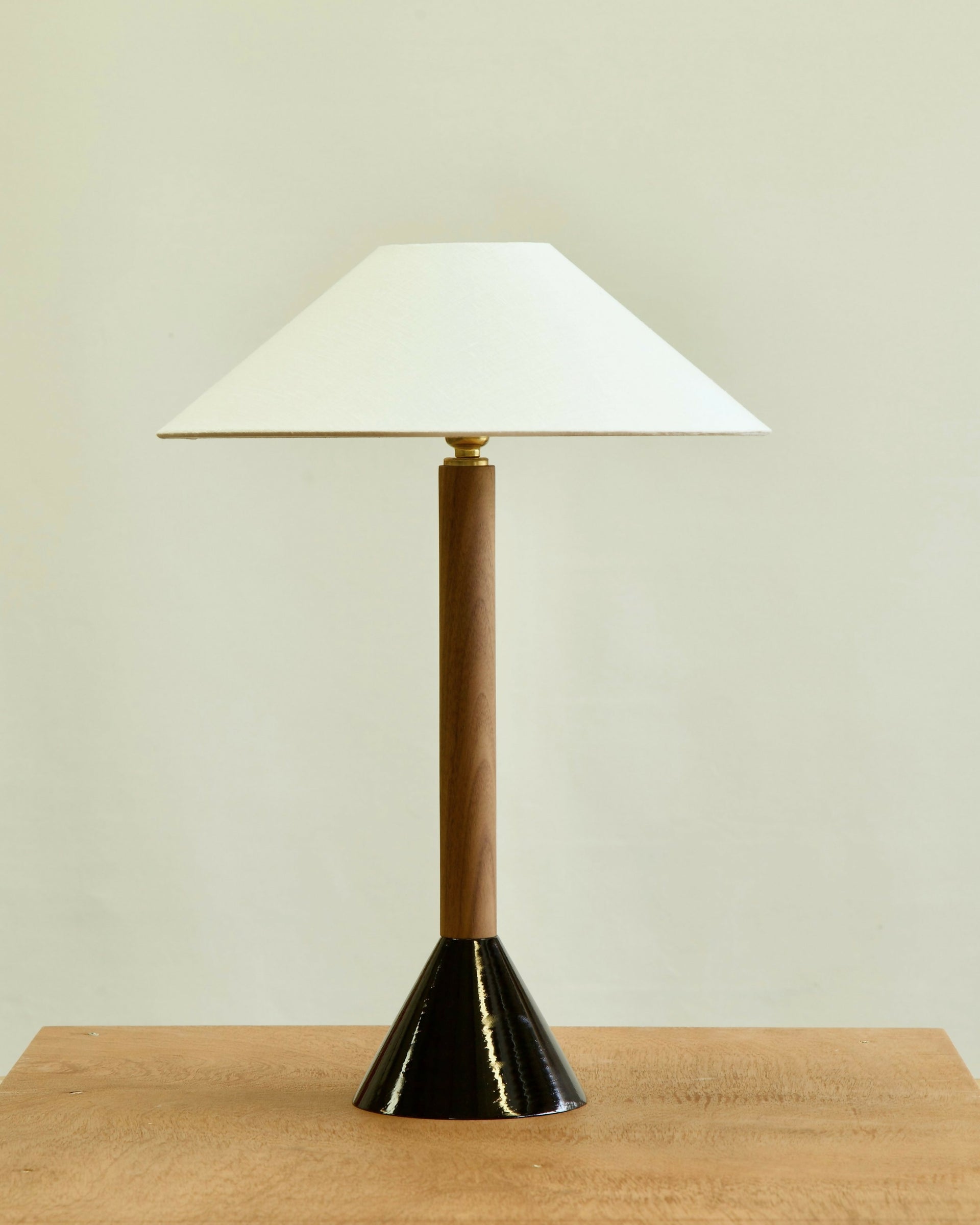 Table lamp with white shade and gold and black base on a wooden surface-available  to buy on the-salon.com. SALON curates the finest , unique, handmade pieces from the interior industry's best makers and brands. Shop luxury furniture, lighting, rugs, art, antiques and vintage pieces and accessories from SALON interior designed rooms.